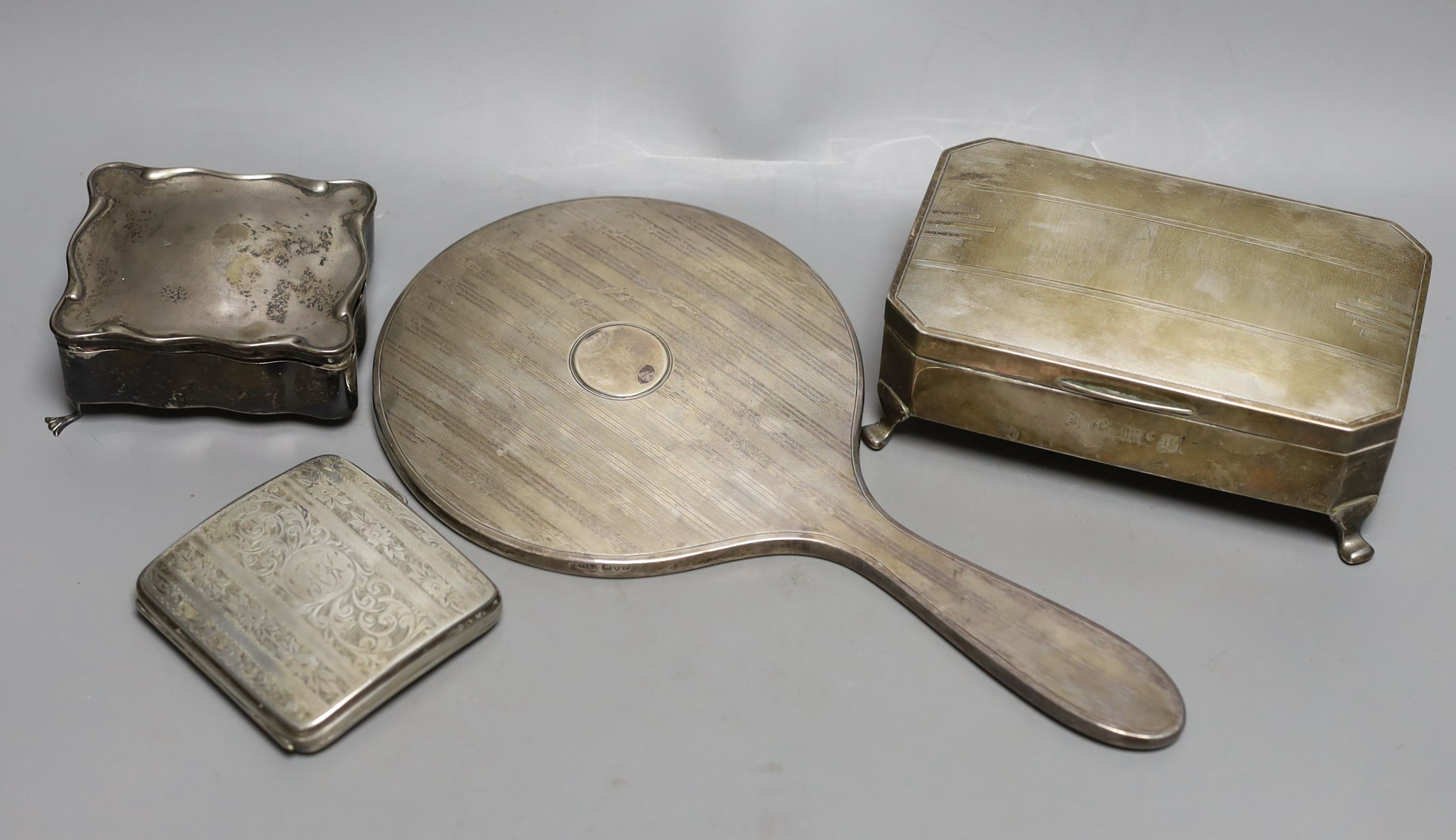 An Art Deco silver mounted cigarette box, a silver cigarette box, silver trinket box and a silver mounted hand mirror.